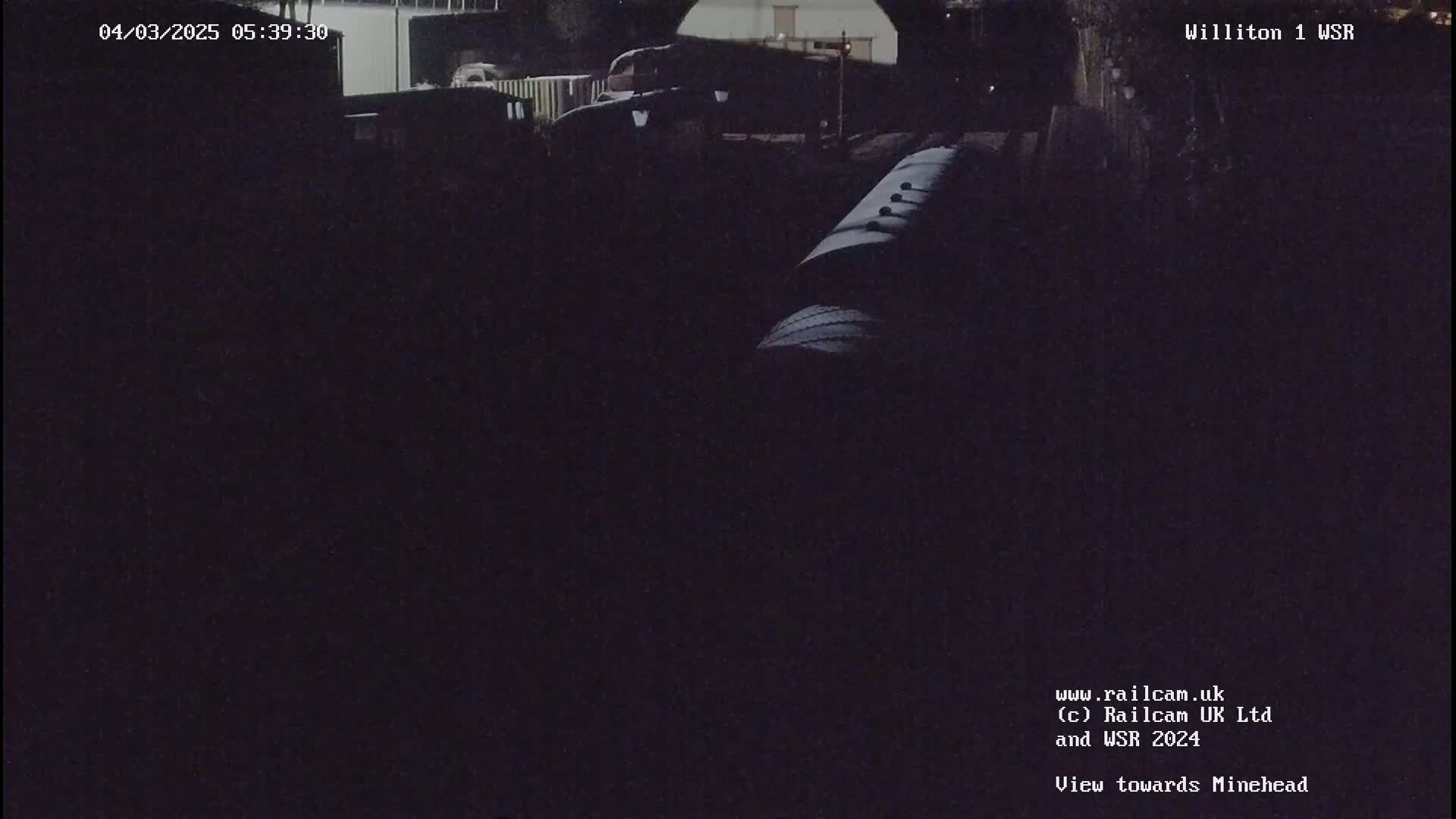 A dark nighttime view of railway cars and structures.