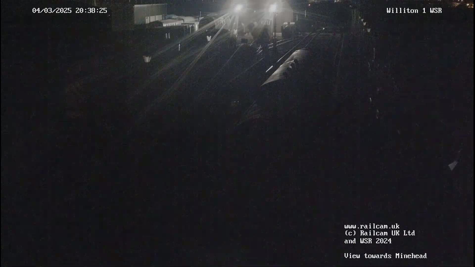 A nighttime view of a dark train on railway tracks.