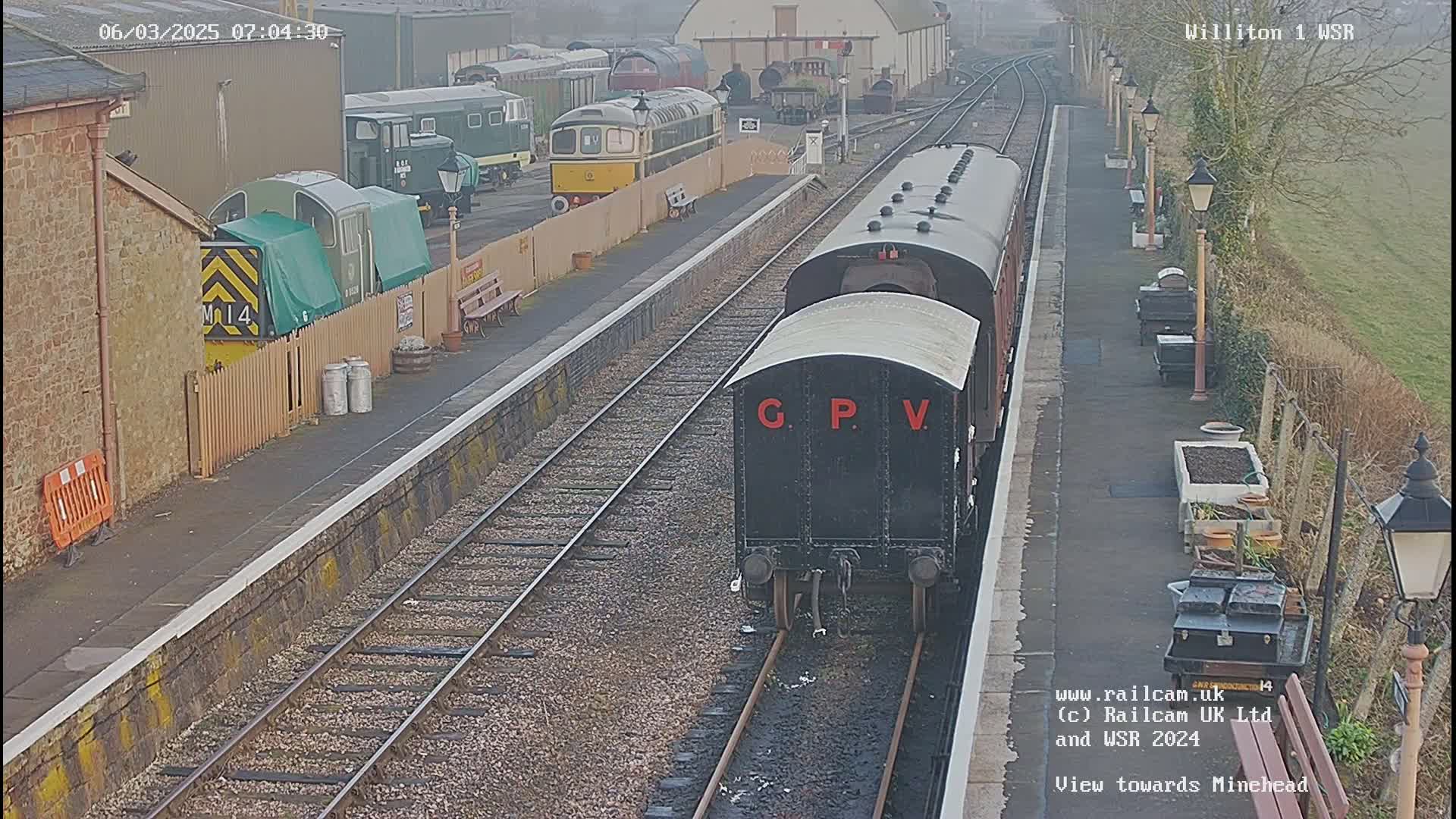 A train is arriving at a railway station on a slightly overcast day.