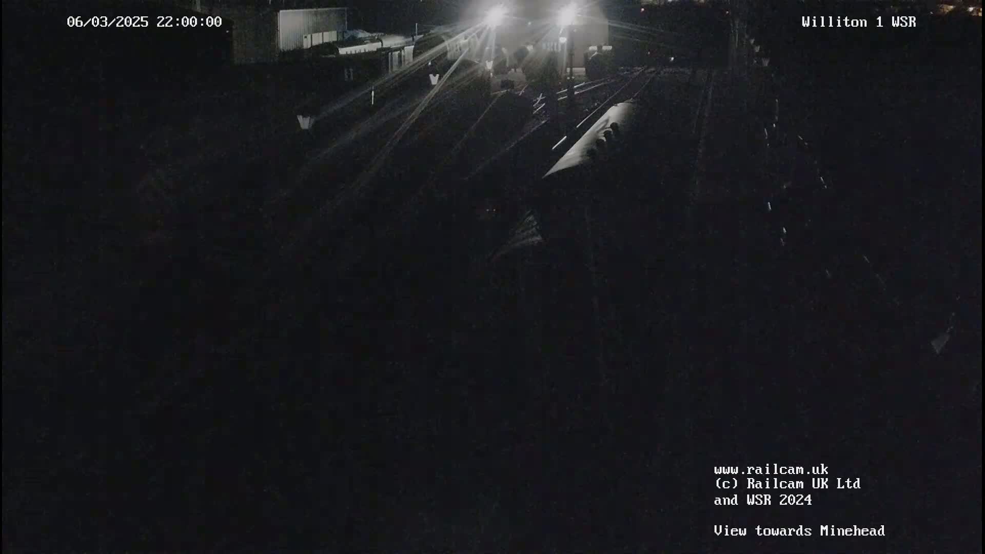 A nighttime, dimly lit view of a railway track with a train partially visible.