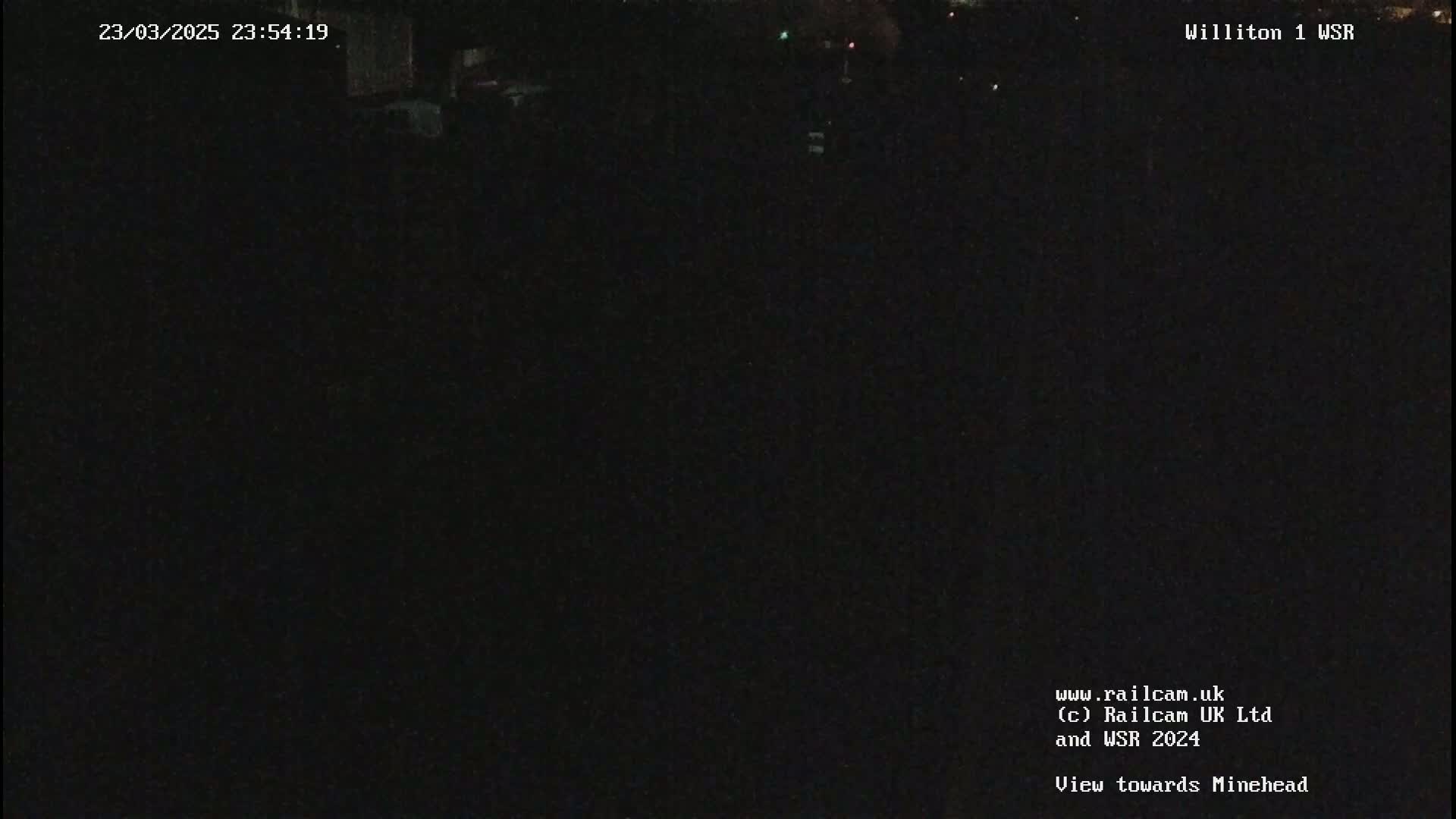 A nighttime, dark image shows only a few indistinct lights in the distance.