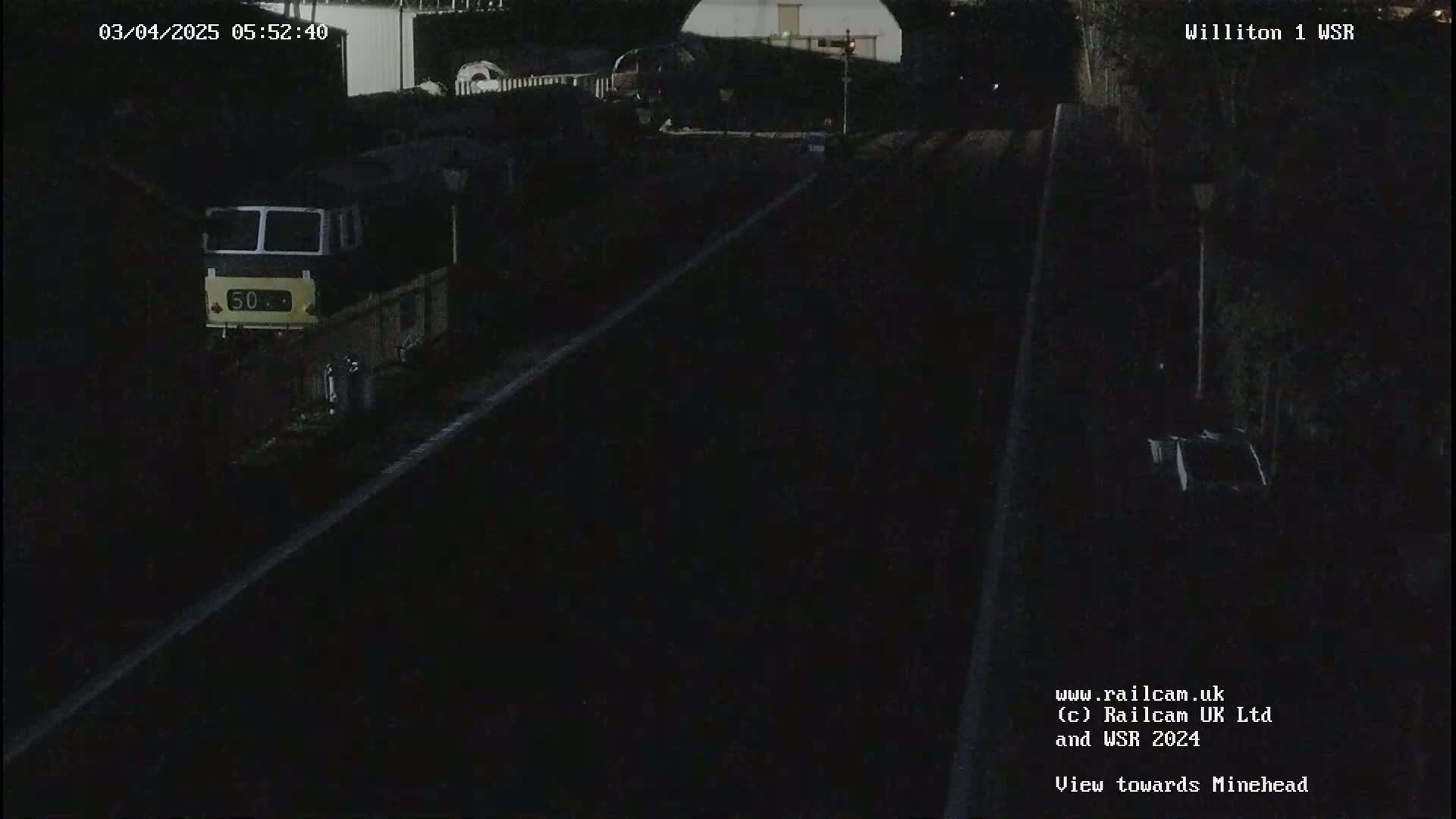 A nighttime view of a train partially visible on railway tracks.