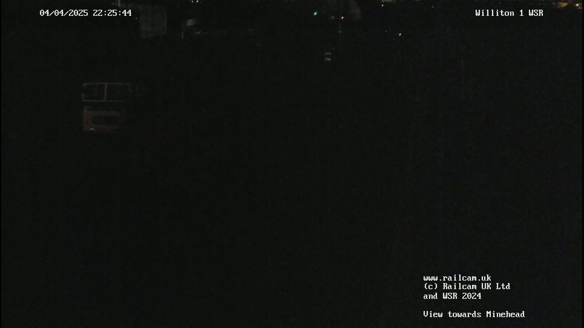 A nighttime, dark view of a mostly obscured object, possibly a vehicle, in an outdoor setting.