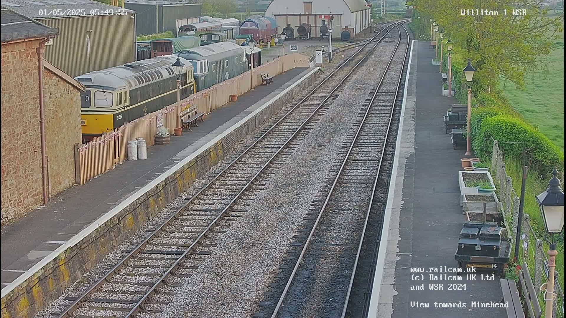A train station with multiple train cars and tracks, viewed on an overcast day.