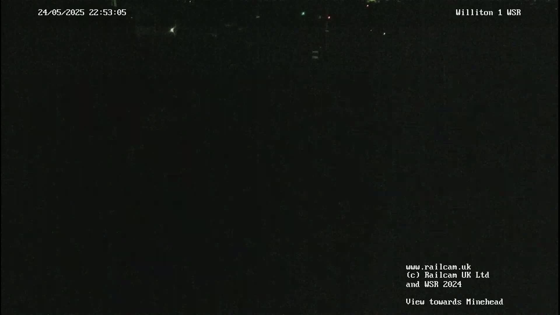 A very dark nighttime scene is visible, with only a few faint lights in the distance.