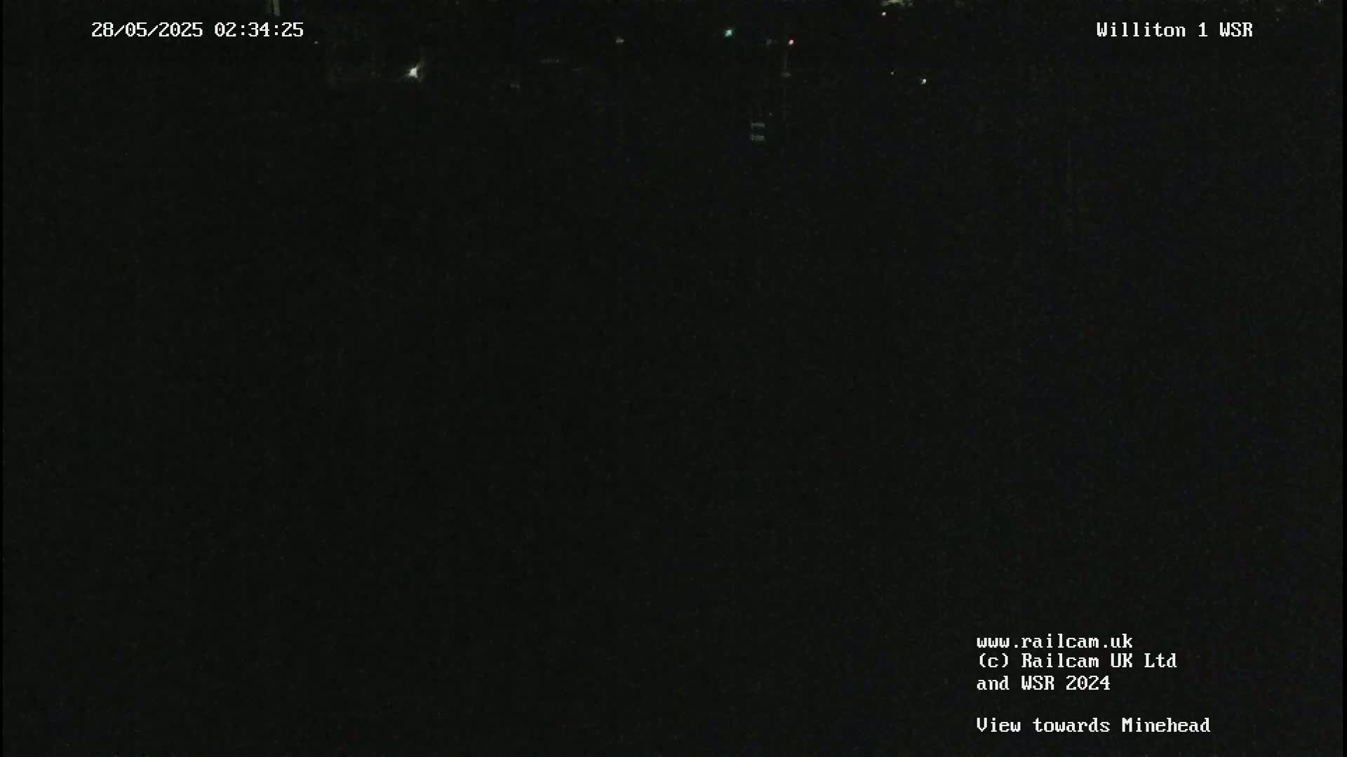 A nighttime, dark view of an outdoor scene with a few faint lights in the distance.