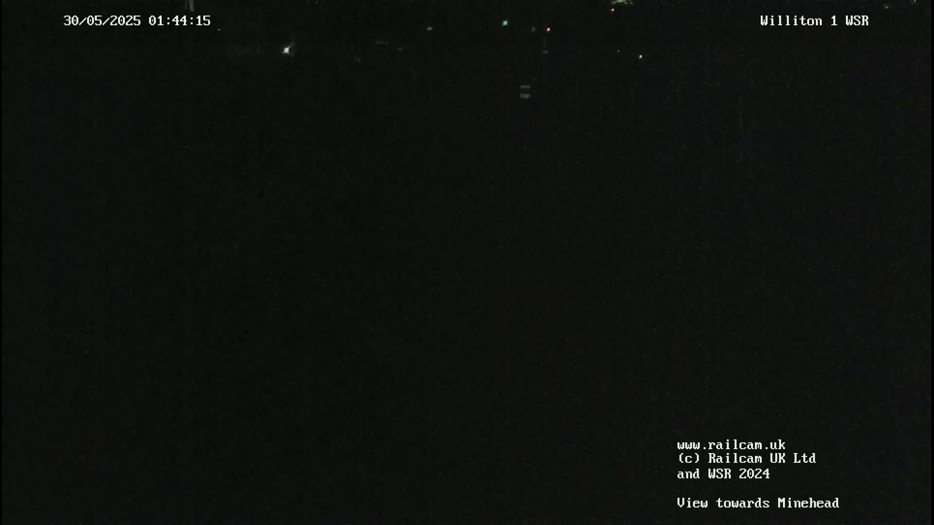 A nighttime view of a dark, possibly rural area with a few distant lights visible.