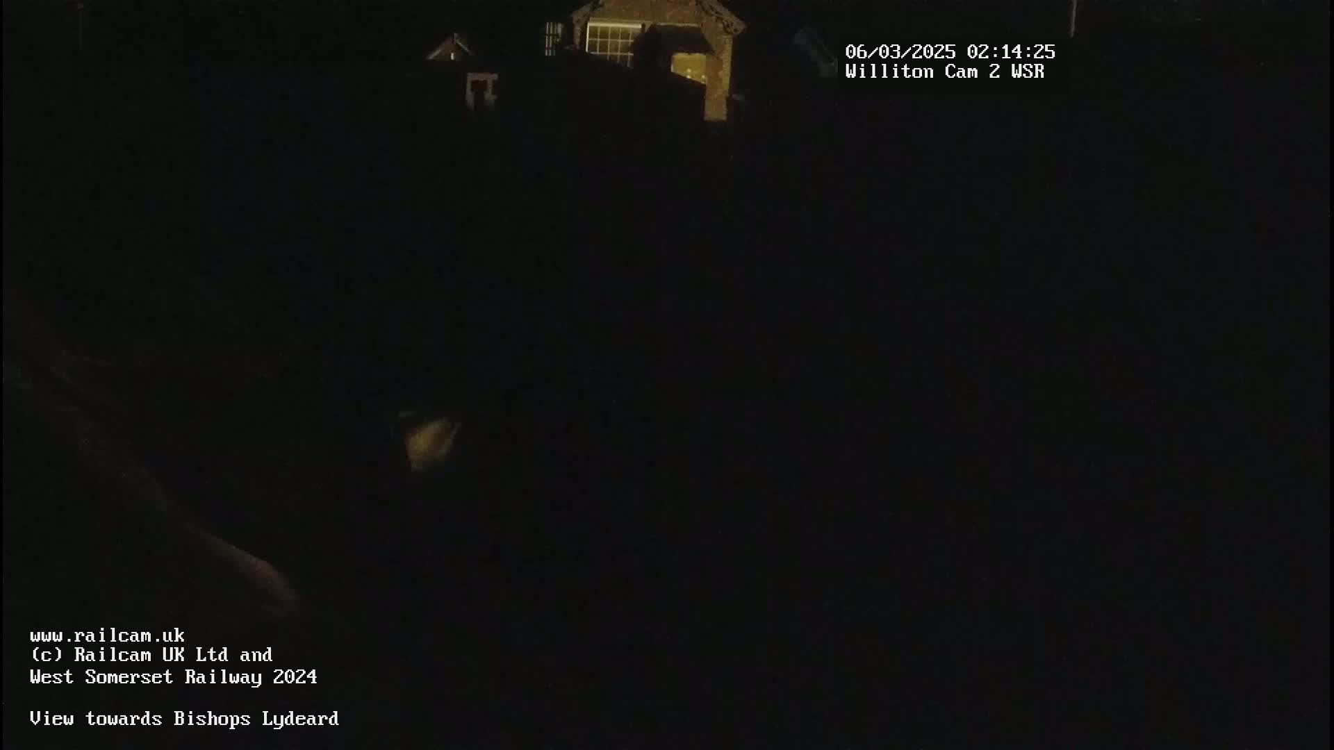 A nighttime, dark view of a building, with only a small amount of light visible.