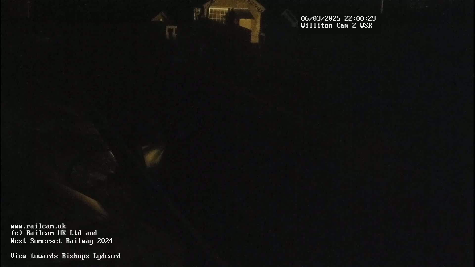 A dark, nighttime image shows dimly lit buildings in the distance.