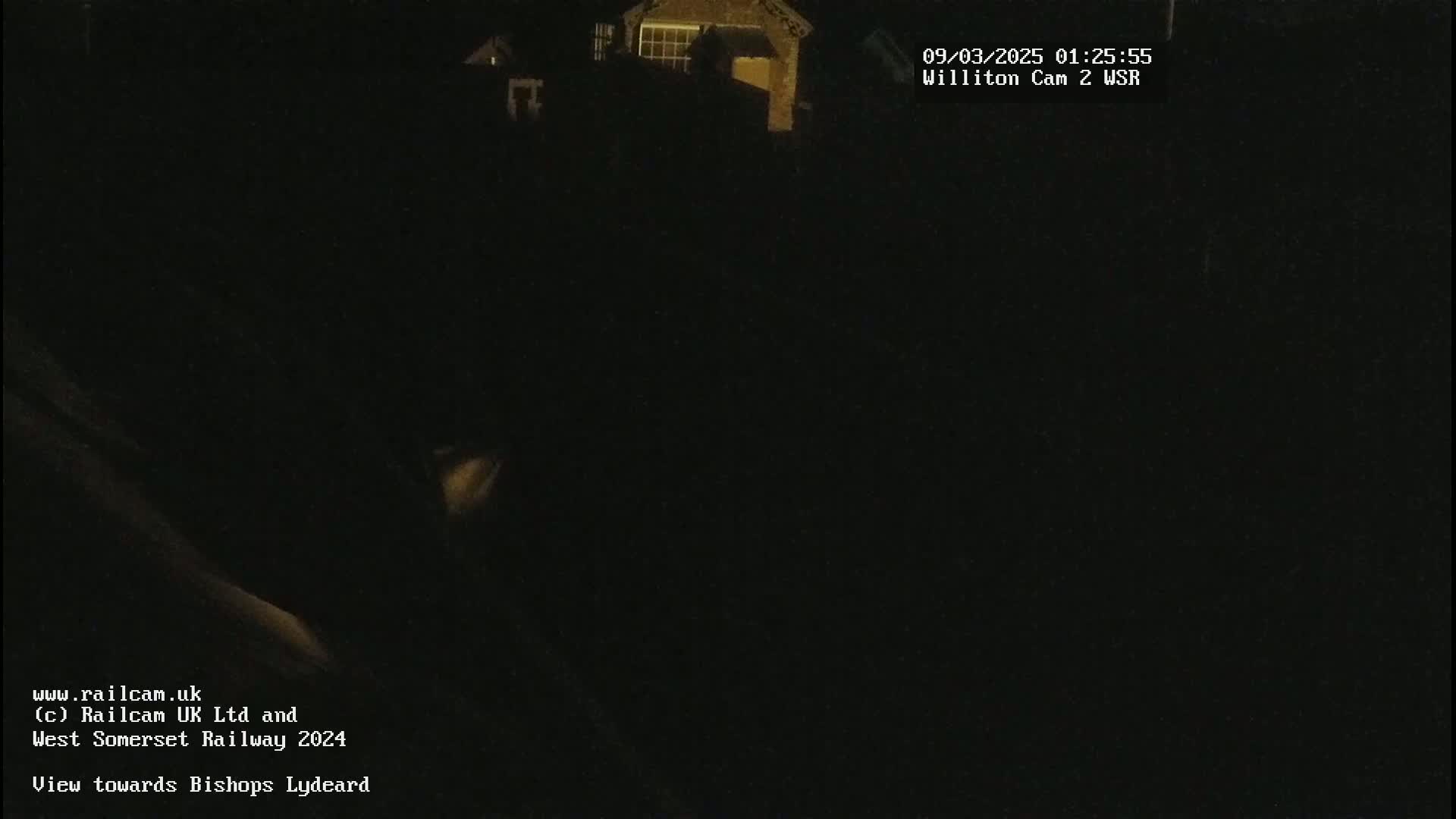 A dark, nighttime scene shows a building lit faintly in the distance.