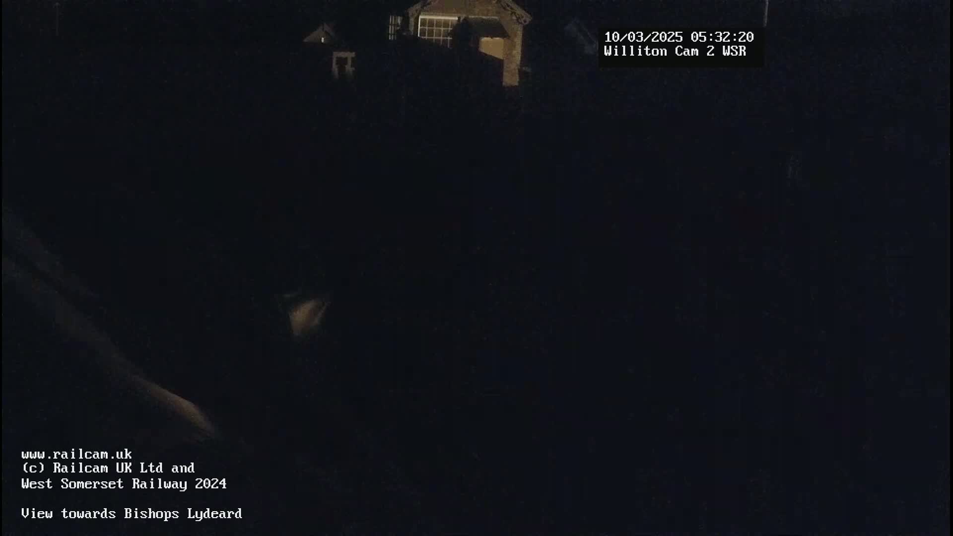 A dark, nighttime scene shows a dimly lit building in the distance.
