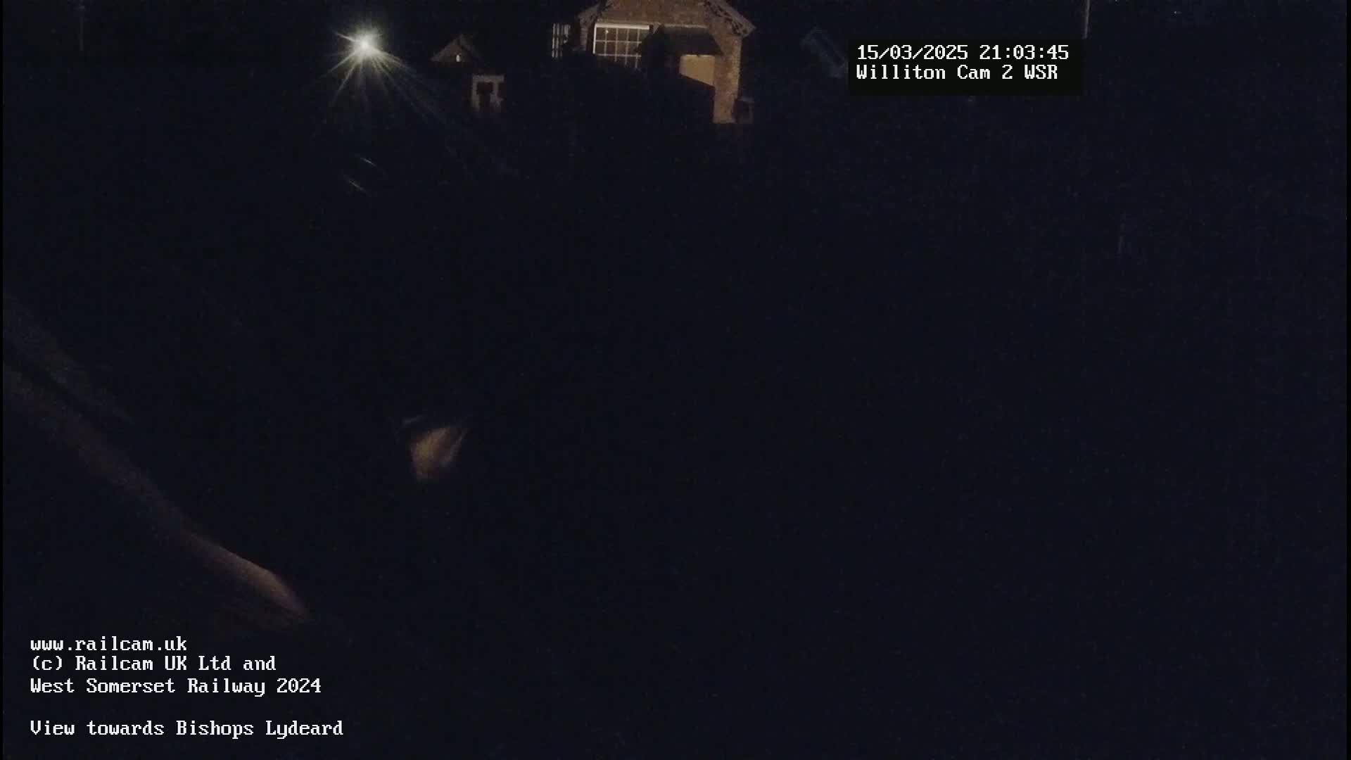 A nighttime, dark view of a building and surrounding area illuminated by a single bright light source.