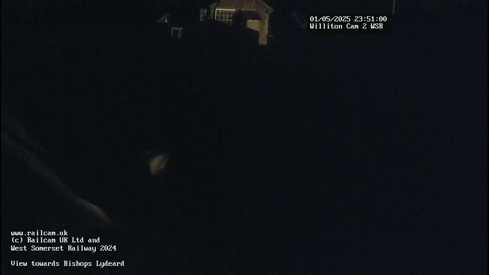 A dark nighttime scene shows a dimly lit building in the distance.