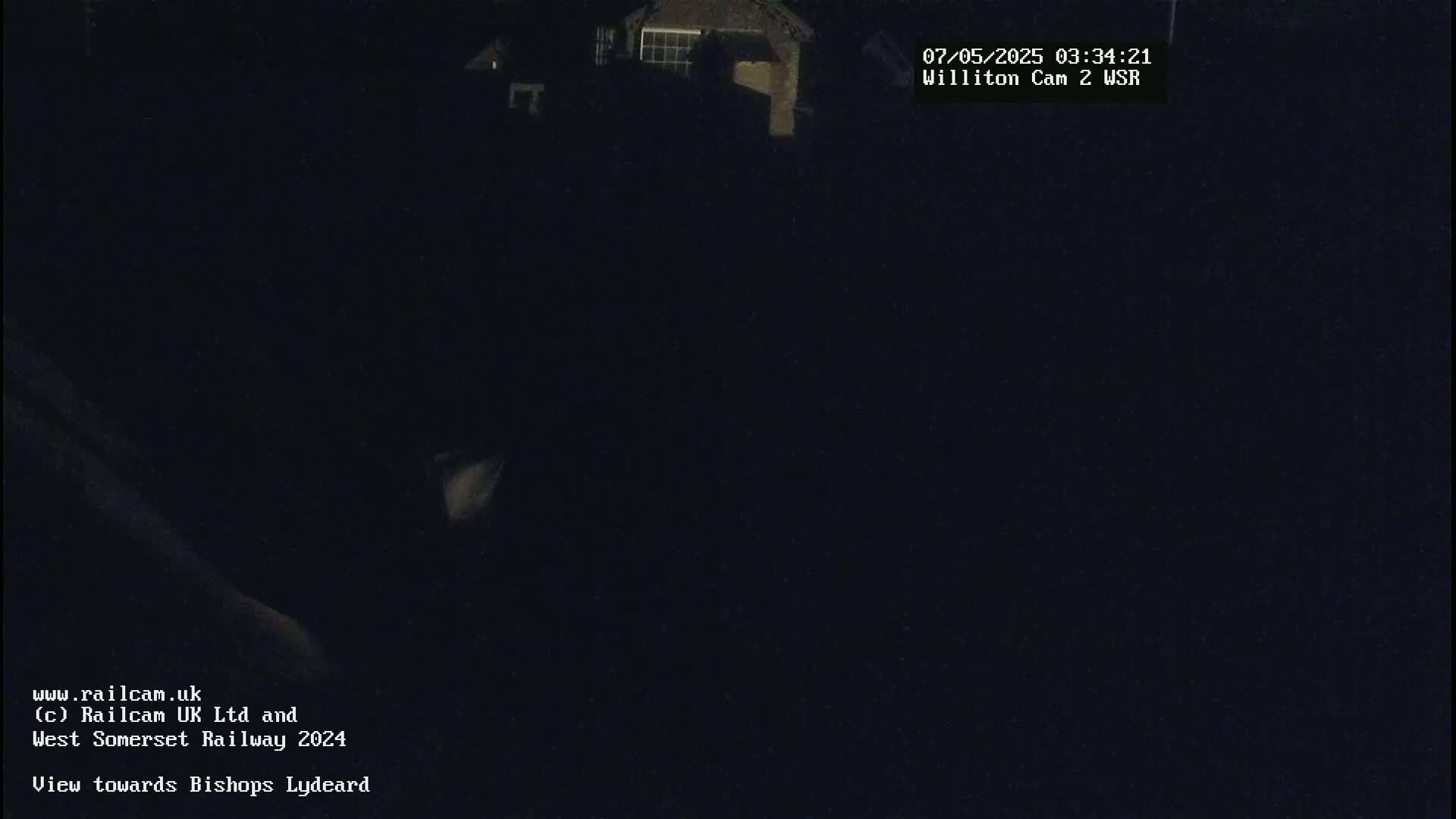 A dark nighttime scene shows a dimly lit building in the distance.