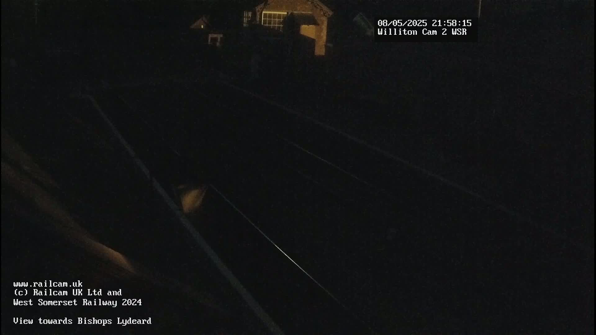 A nighttime view of train tracks, with a building dimly visible in the background.