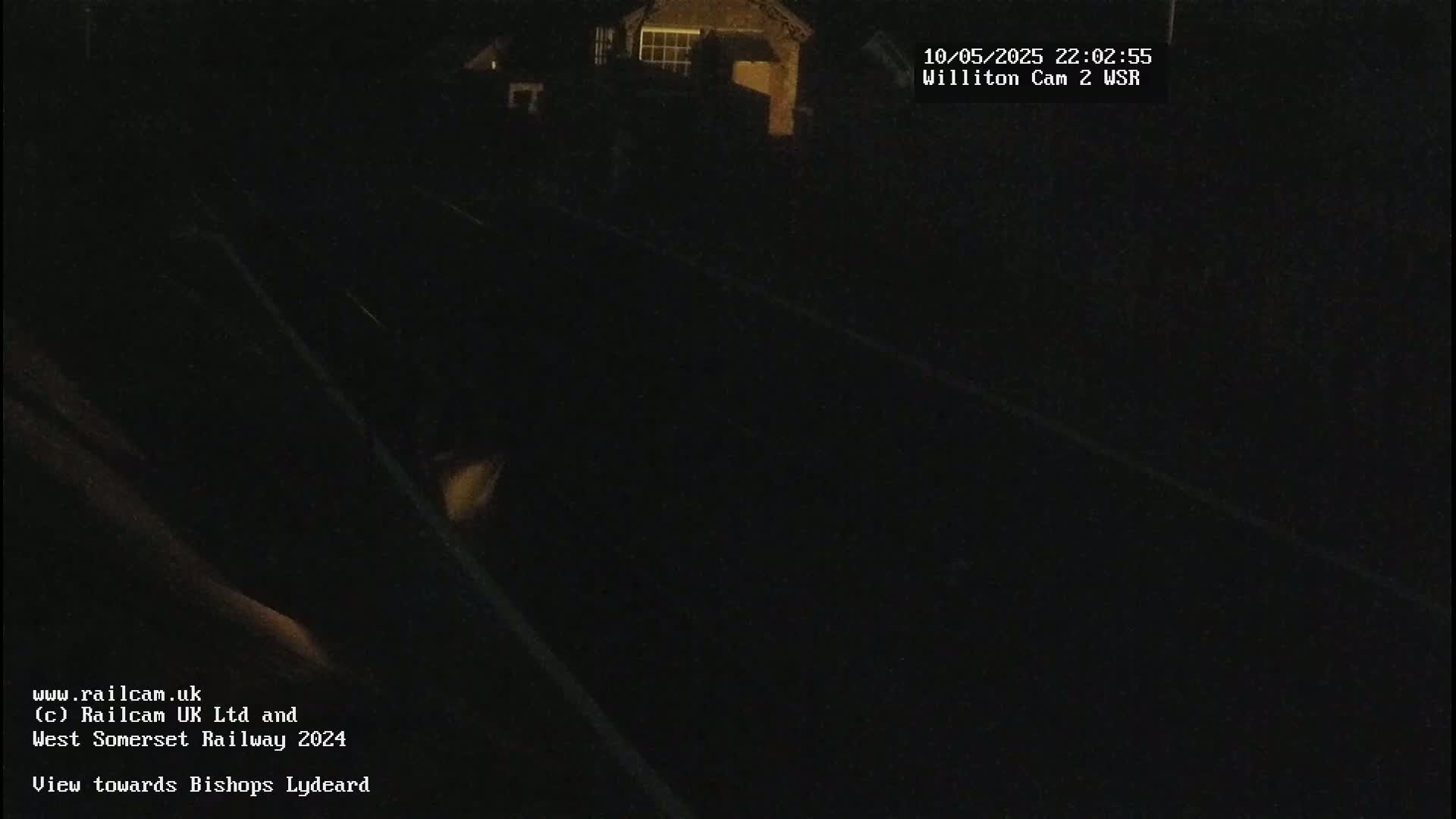 A dark, nighttime view of train tracks near a building.