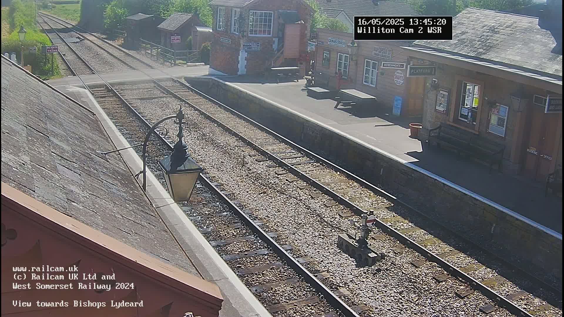 A sunny view of a train station with train tracks extending into the distance.