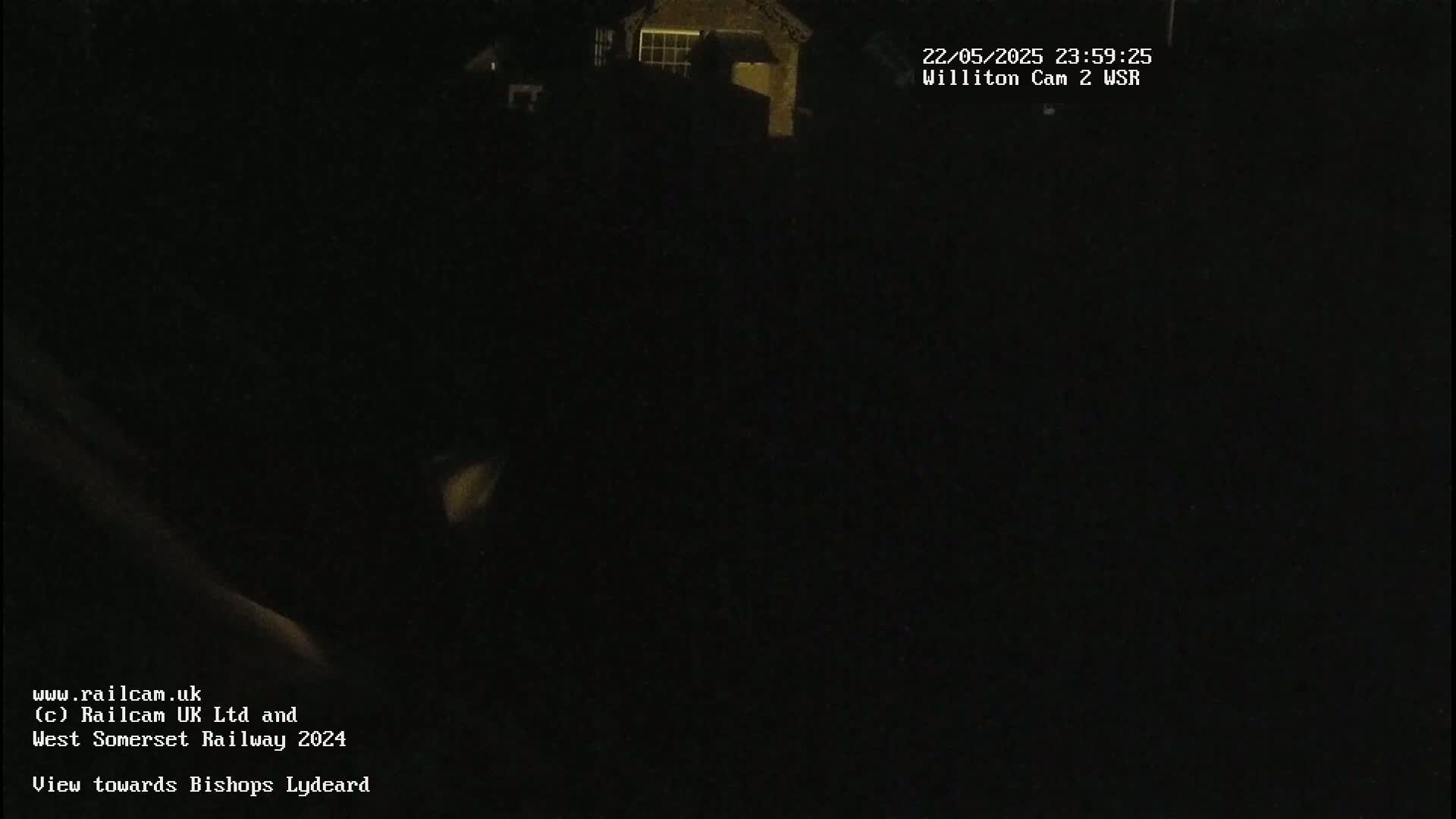 A dark, nighttime view of a building with a few dimly lit windows.