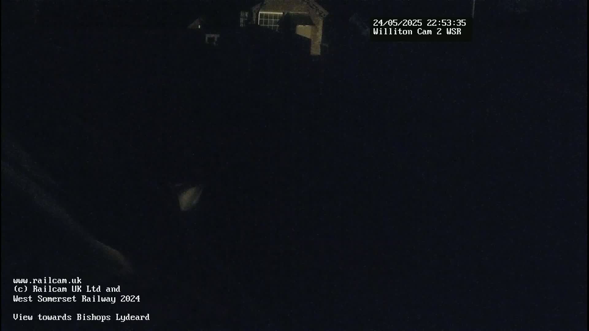 A nighttime, dark outdoor scene shows a building in the distance under a clear, dark sky.
