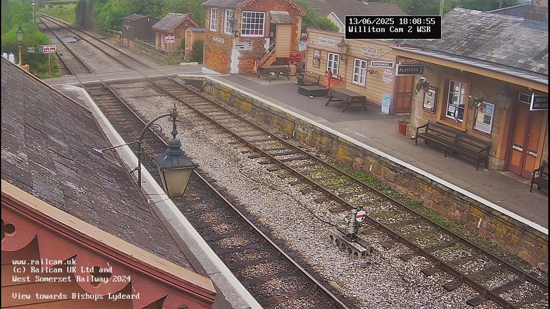 A view of a train station platform and railway tracks on an overcast day.
