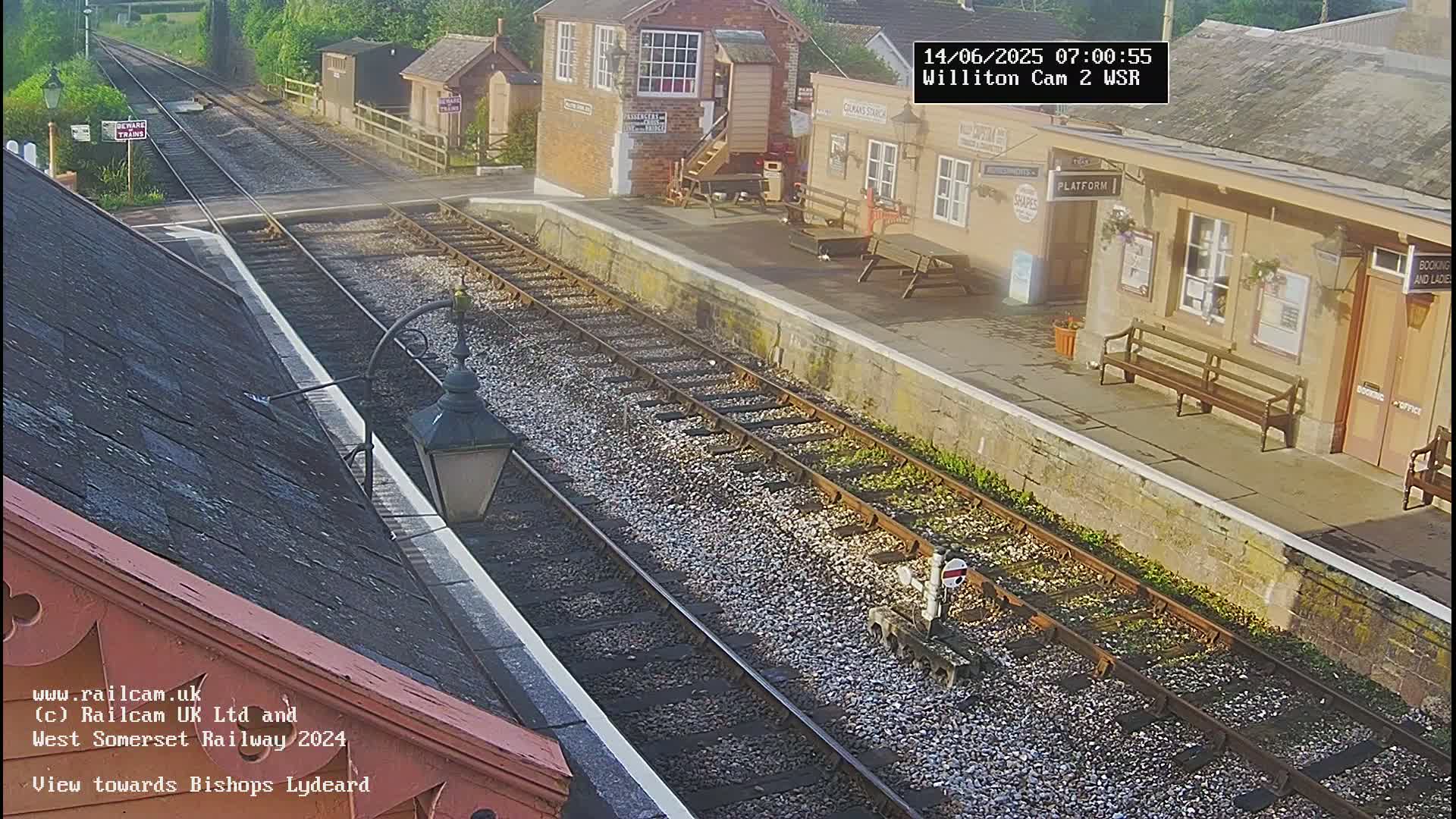 A view of a train station platform and railway tracks on an overcast day.