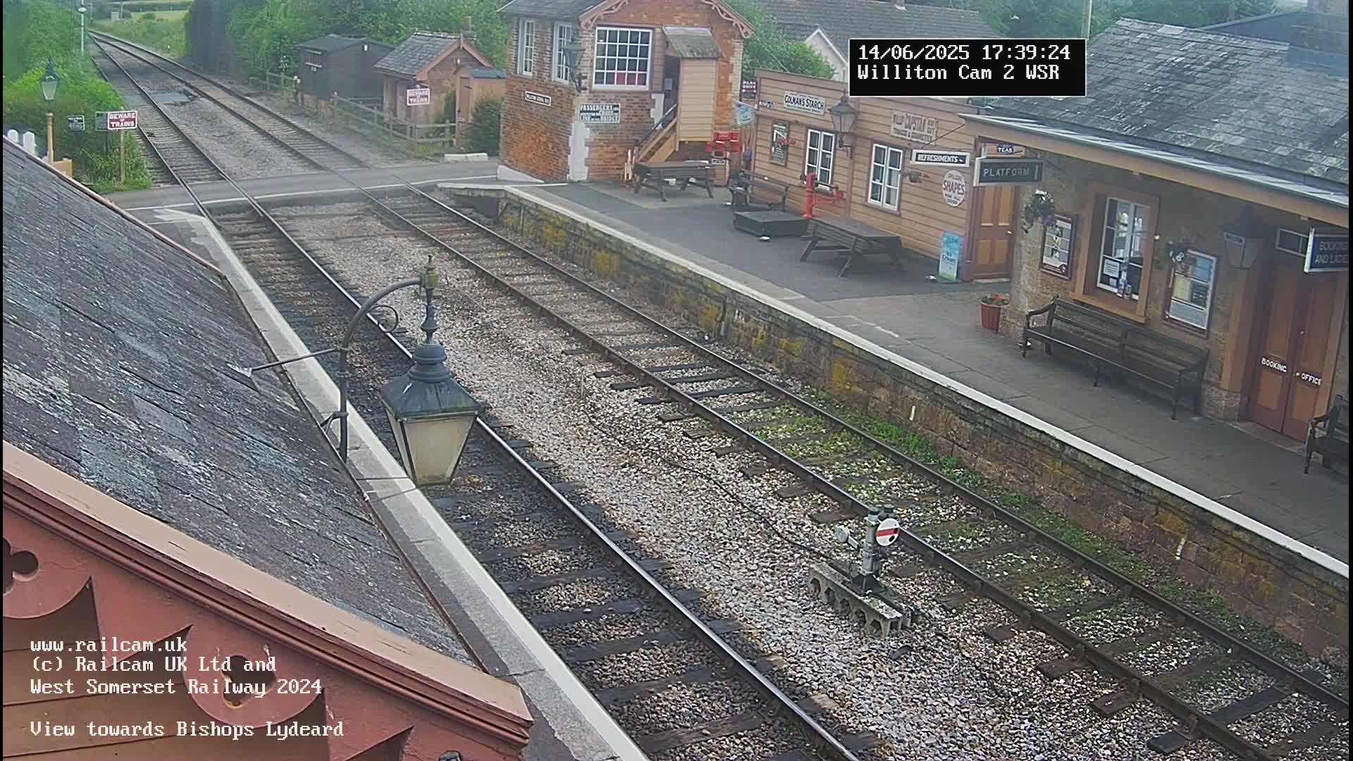 A view of a train station platform and railway tracks on an overcast day.