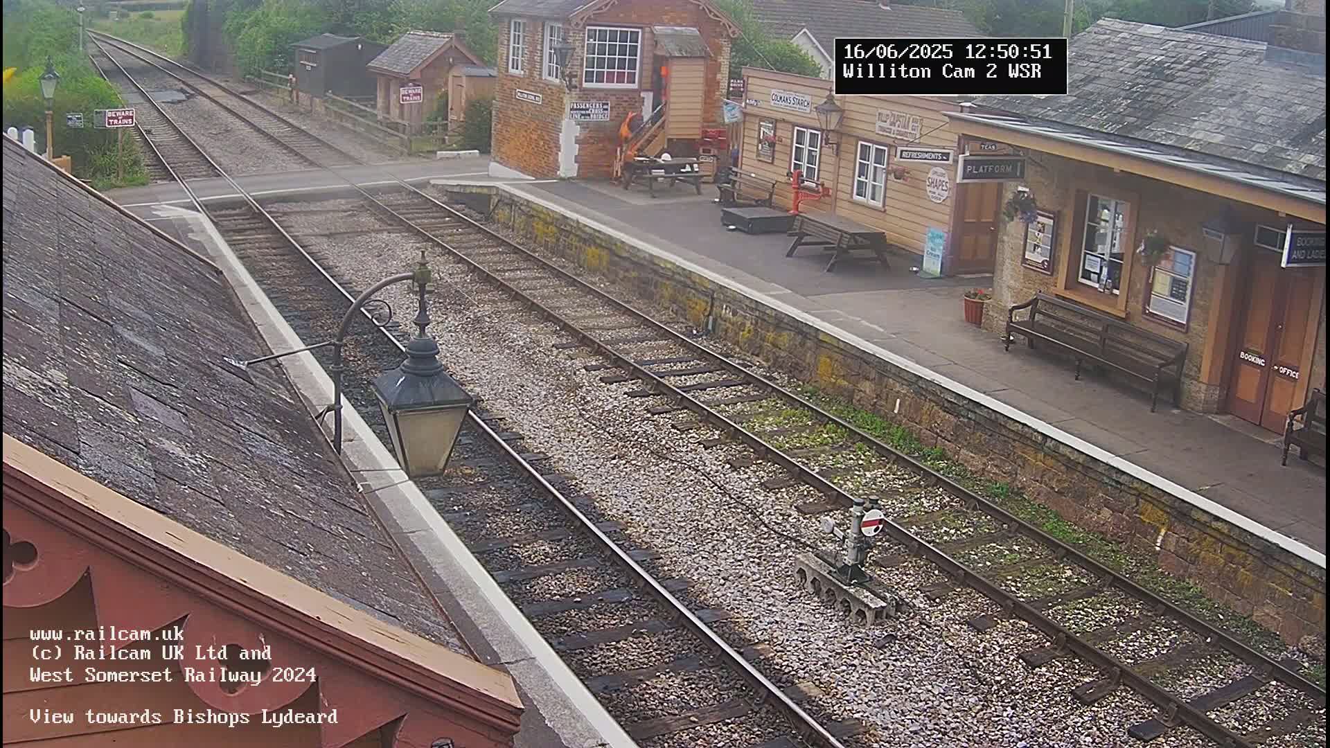 A view of a train station platform and tracks on a partly sunny day.