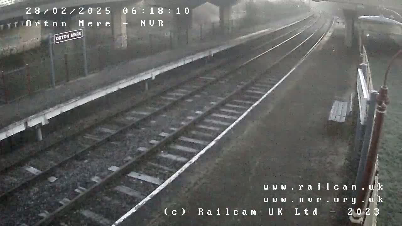 A misty view of a train station platform and railway tracks.