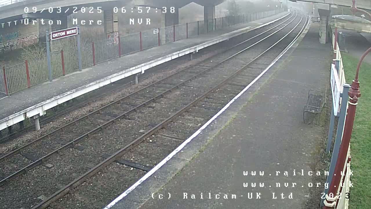 A foggy view of a train platform with two sets of railway tracks.