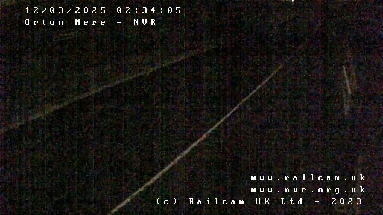 A dark, nighttime image shows a diagonal line, possibly a wire or track, against a mostly black background.