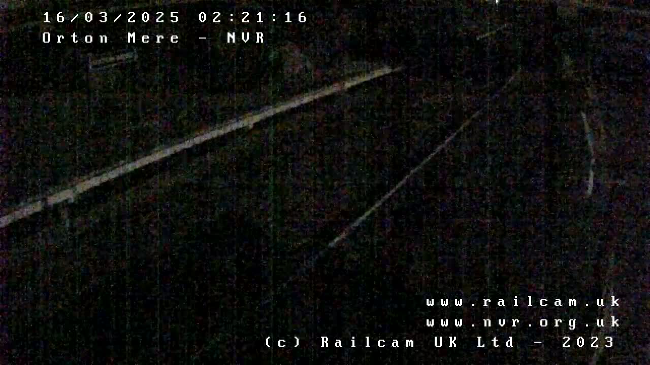 A nighttime, low-light view of a dark railroad track.