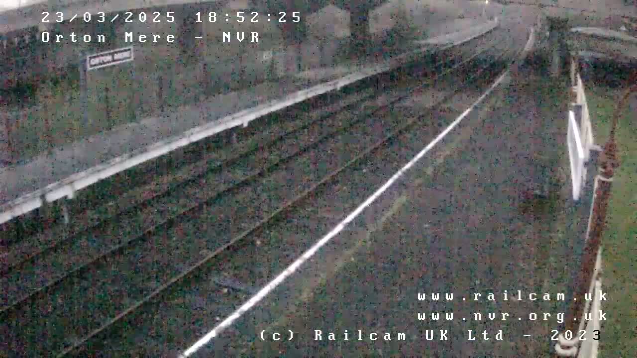 A high-angle, daytime view of train tracks and a railway platform, possibly taken during overcast conditions.