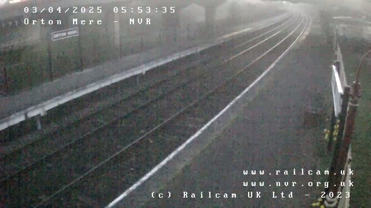 A rain-swept view of train tracks and a station platform.