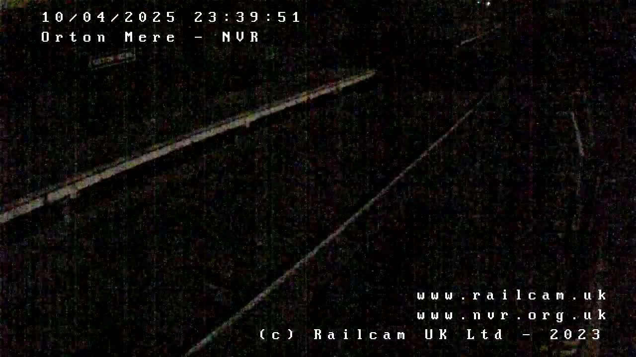A nighttime, low-light view of a dark railroad track.
