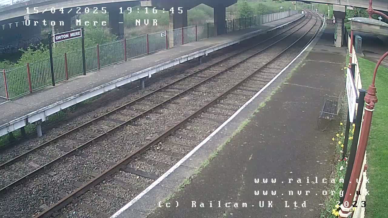 An overcast view of a train platform with two sets of tracks extending into the distance.