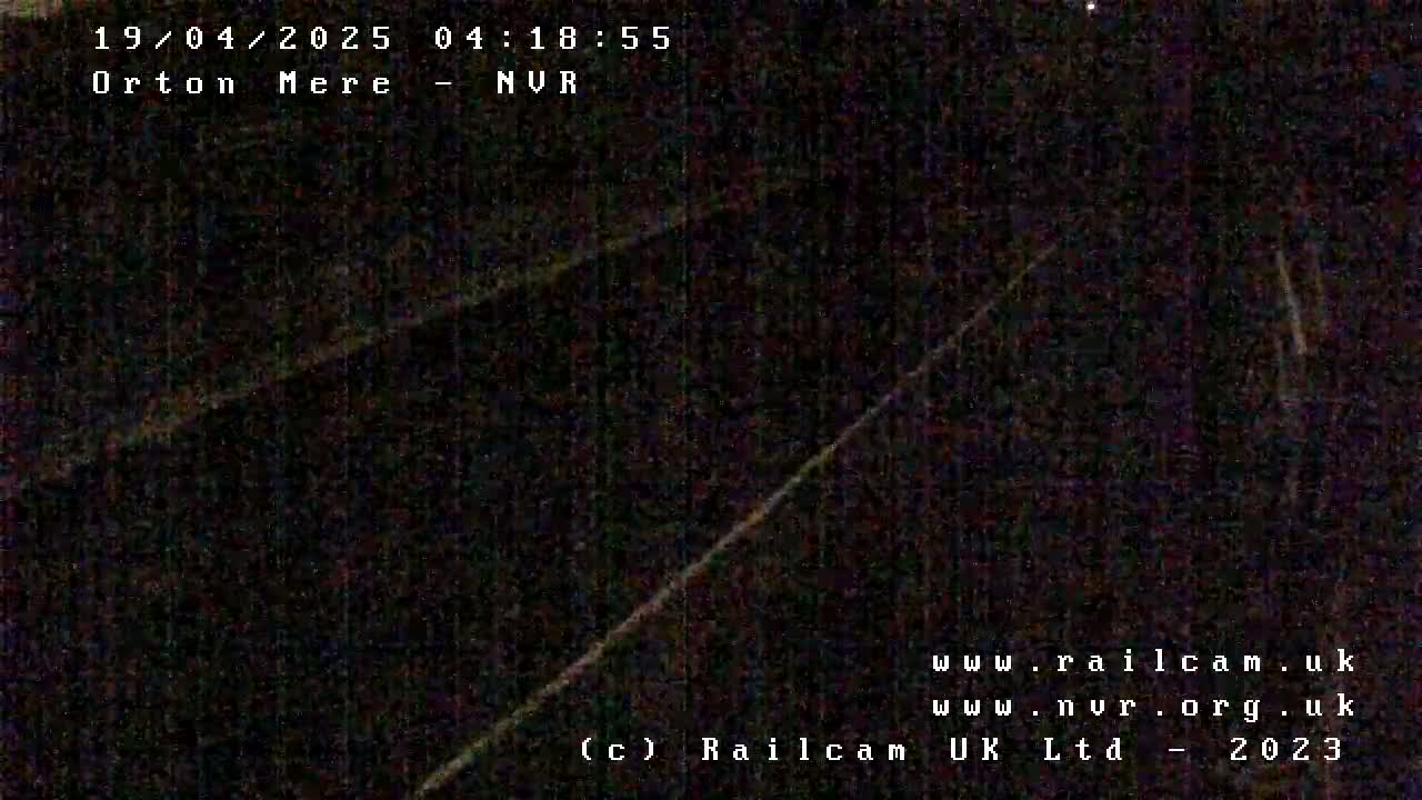 A dark, nighttime image shows a dimly lit railway track.