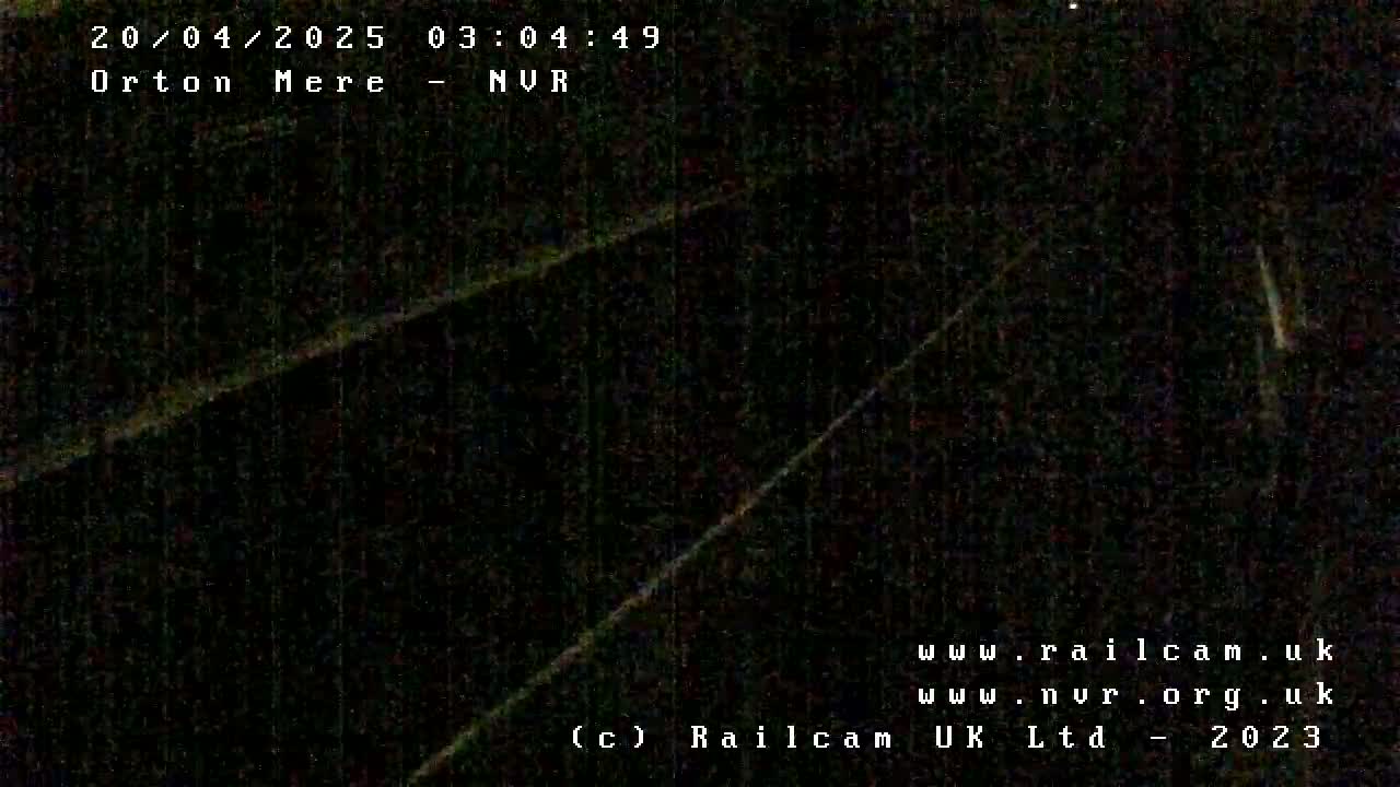 A dark, nighttime image shows two diagonal lines possibly representing railroad tracks or roads.