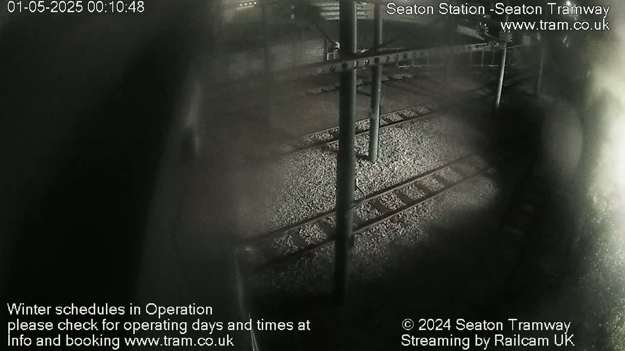 A nighttime, overhead view of train tracks covered in gravel.