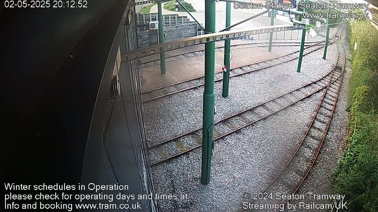A high-angle view shows several train tracks curving around a gravel-covered platform.