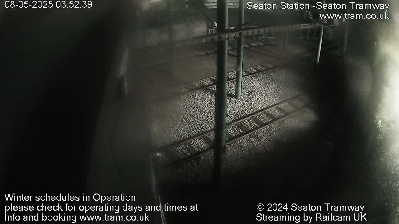 A nighttime, high-angle view of empty tram tracks covered in light-colored gravel.