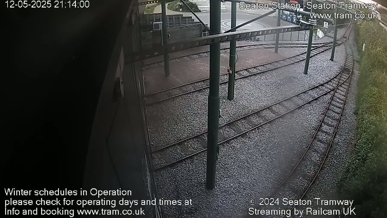 A nighttime view of a tram station's railway tracks and platform.