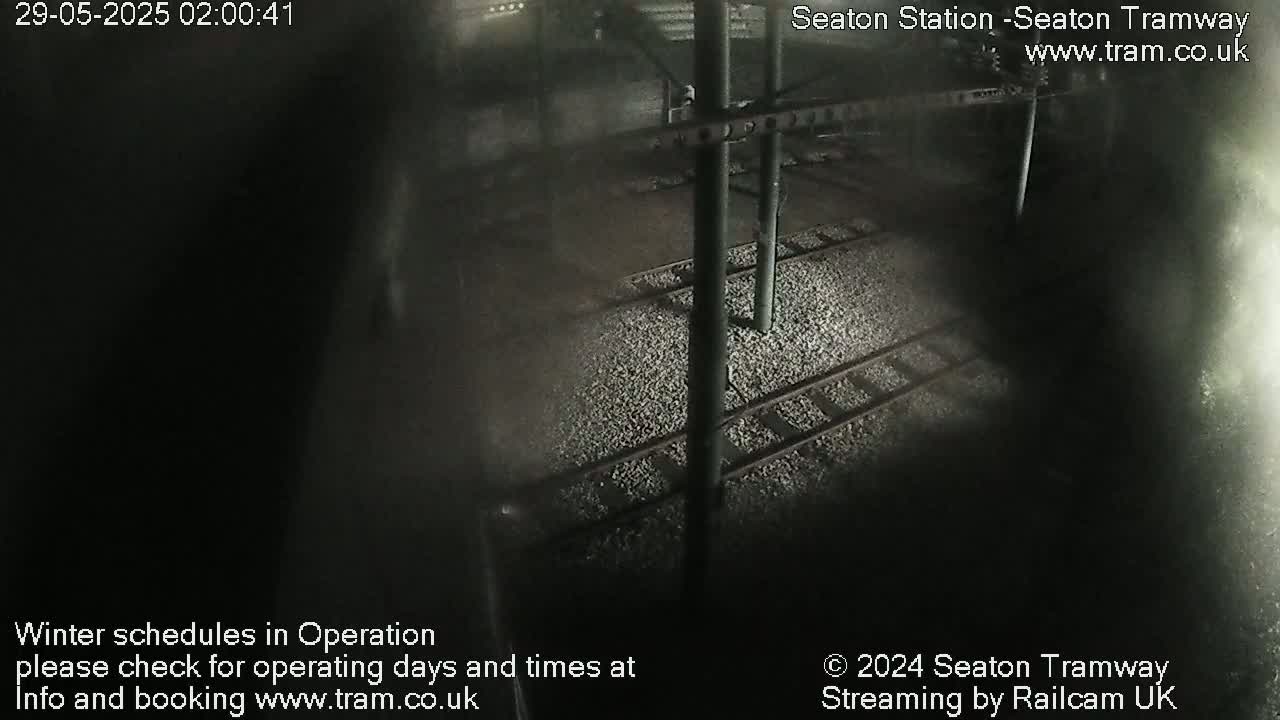A nighttime, high-angle view of train tracks and a gravel bed at a station.
