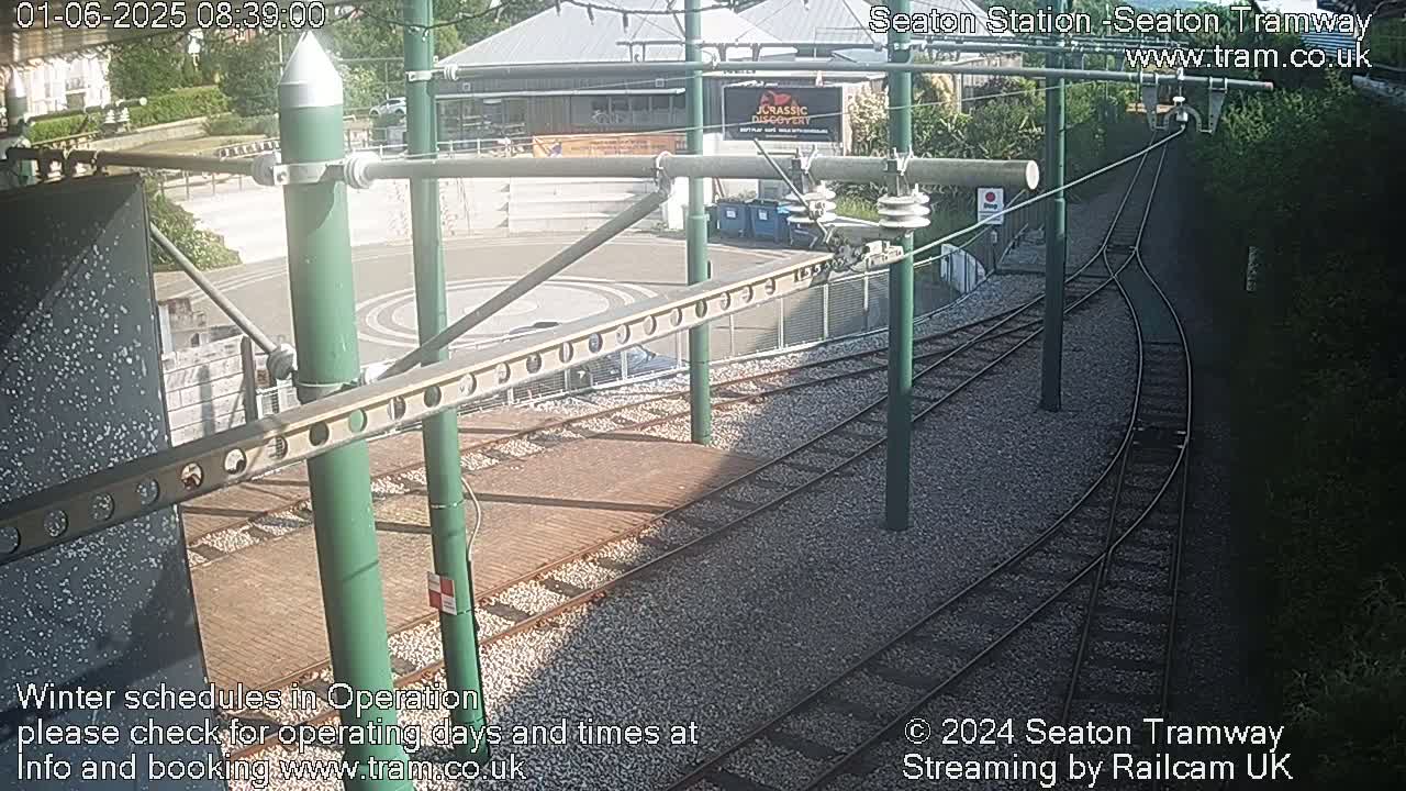 A sunny overhead view of a tram station's turning loop and track system, surrounded by greenery.