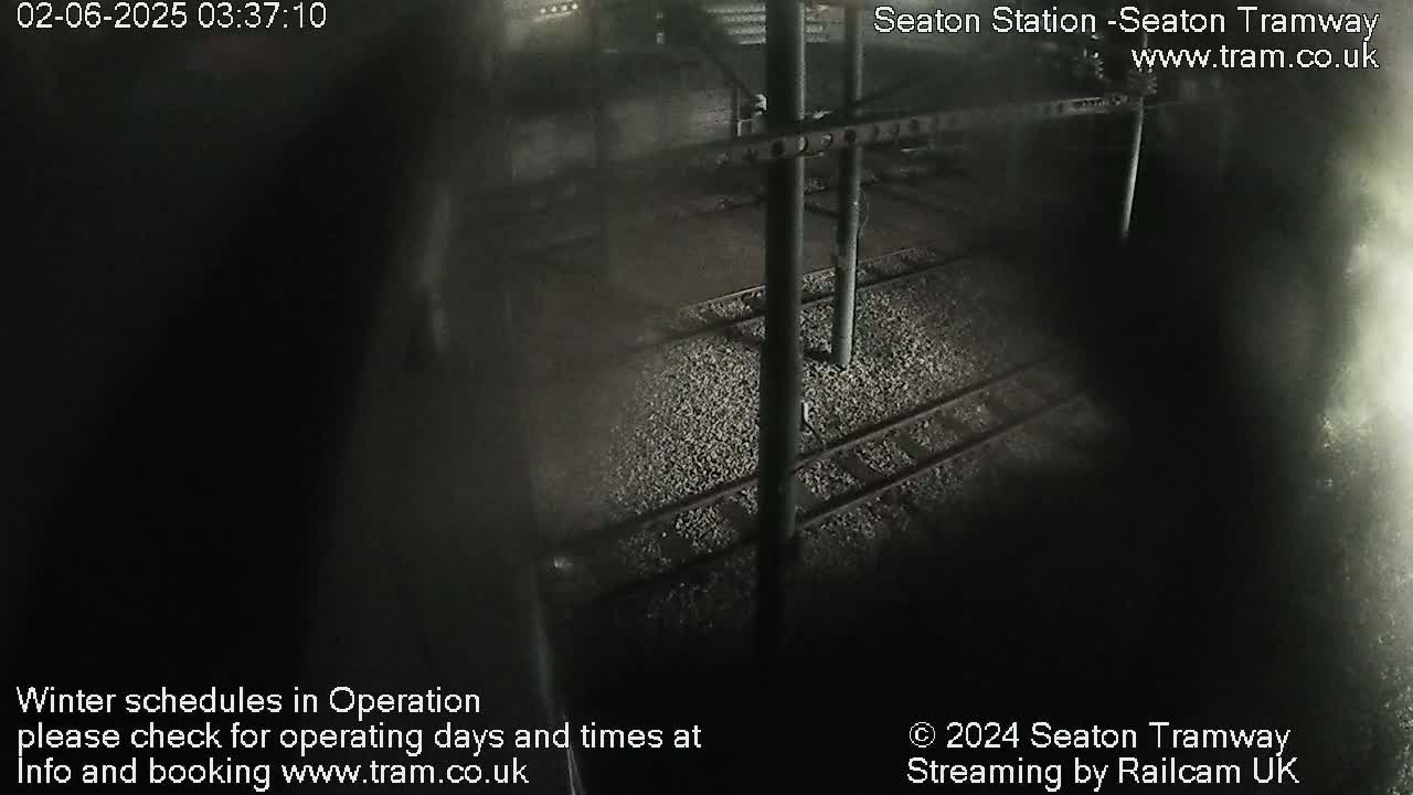 A nighttime, dark view of train tracks at a station.
