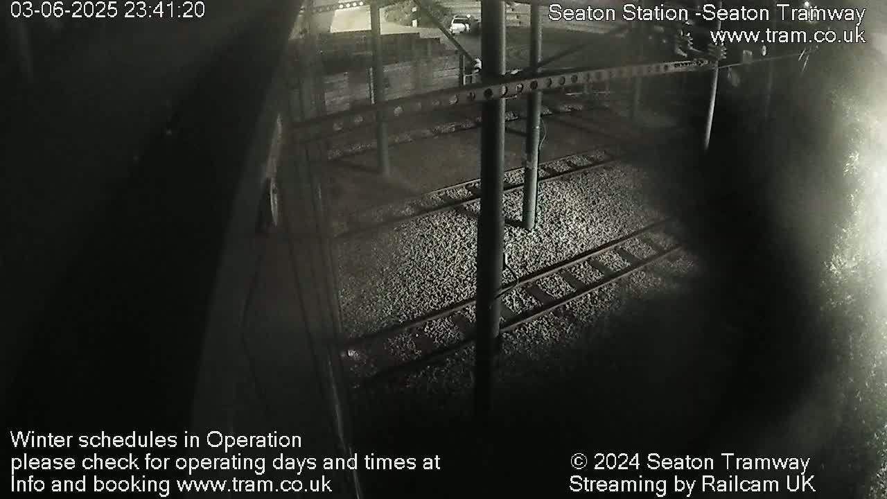 A nighttime overhead view of train tracks and a gravel-covered platform.