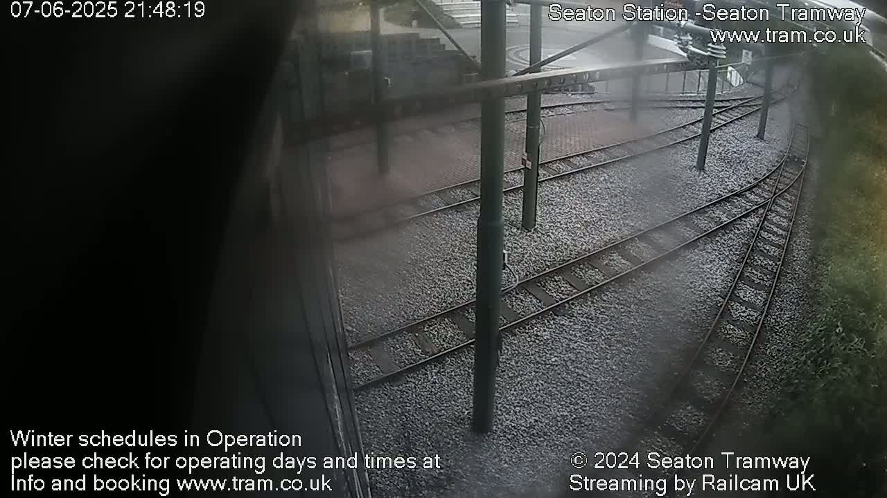A high-angle view of train tracks at a station, possibly at night or in low light.