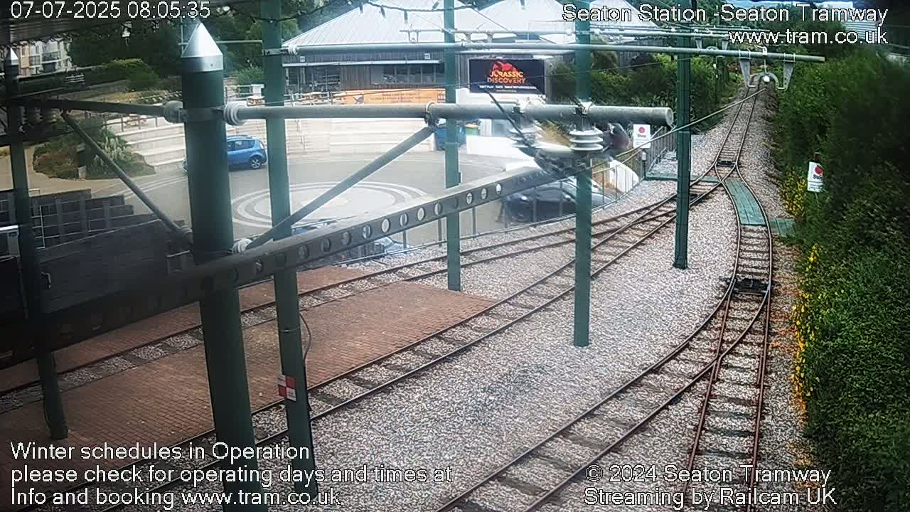 A tram station with a curved track, viewed from above, on an overcast day.
