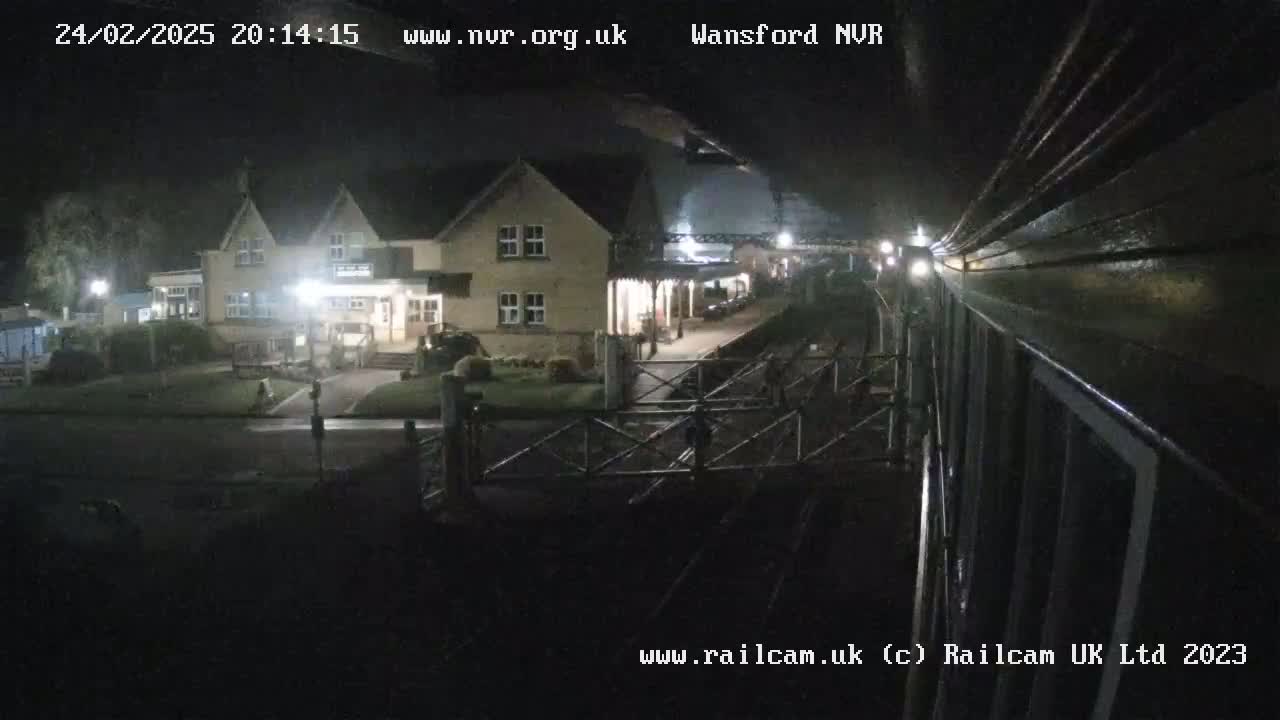 A nighttime view of a building near a train station, seen from a train car.