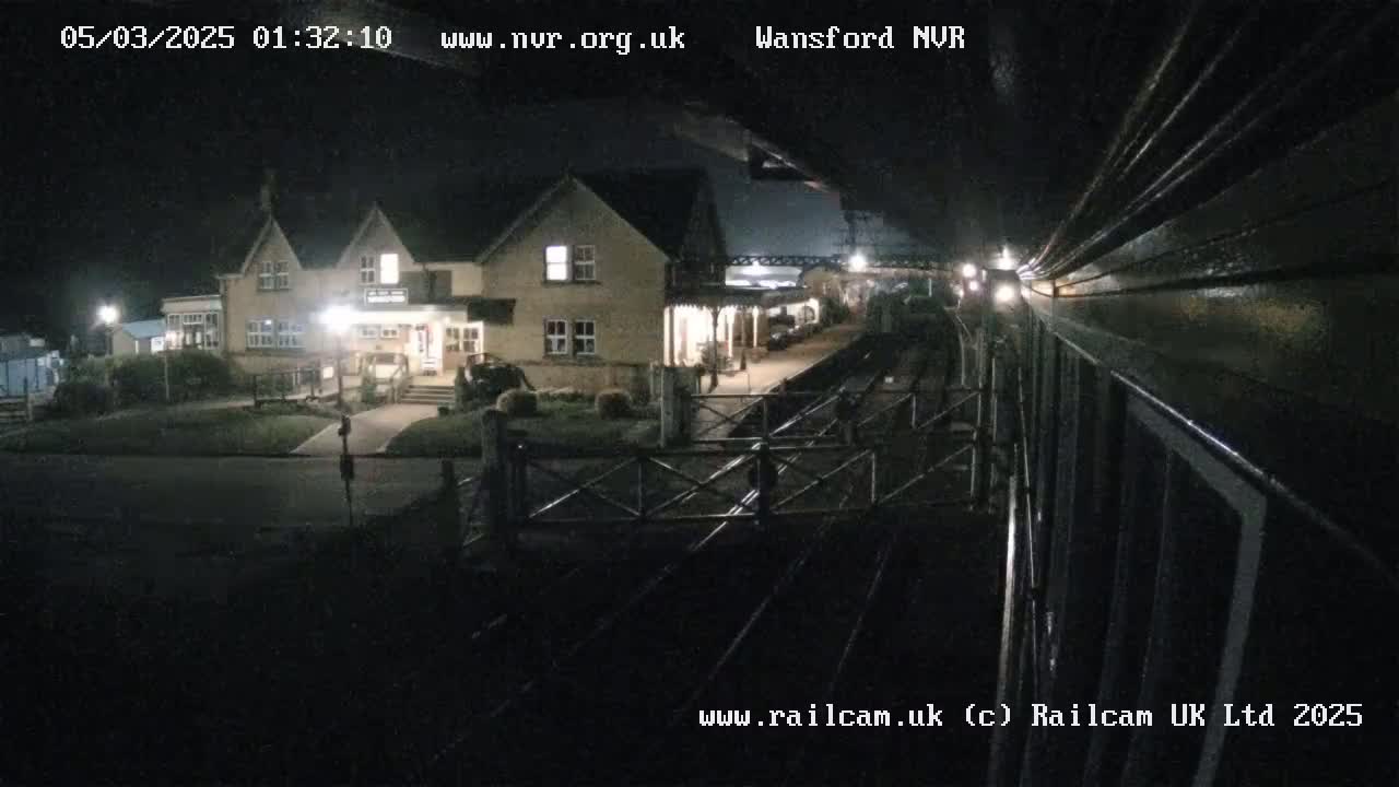 A nighttime view from a train shows a two-story building next to a train station.