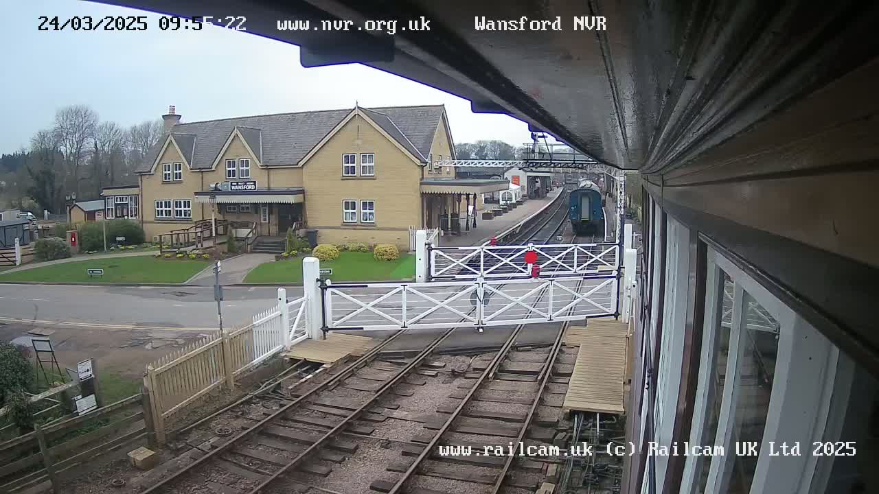 A train passes a railway station building on an overcast day.